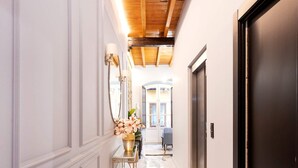 A hallway with marble flooring, a wooden ceiling, and a dark door. - Genteel Home Catedral 201 (Granada)