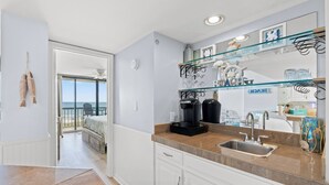 A modern kitchen with a large window, a coffee maker, and a sink.