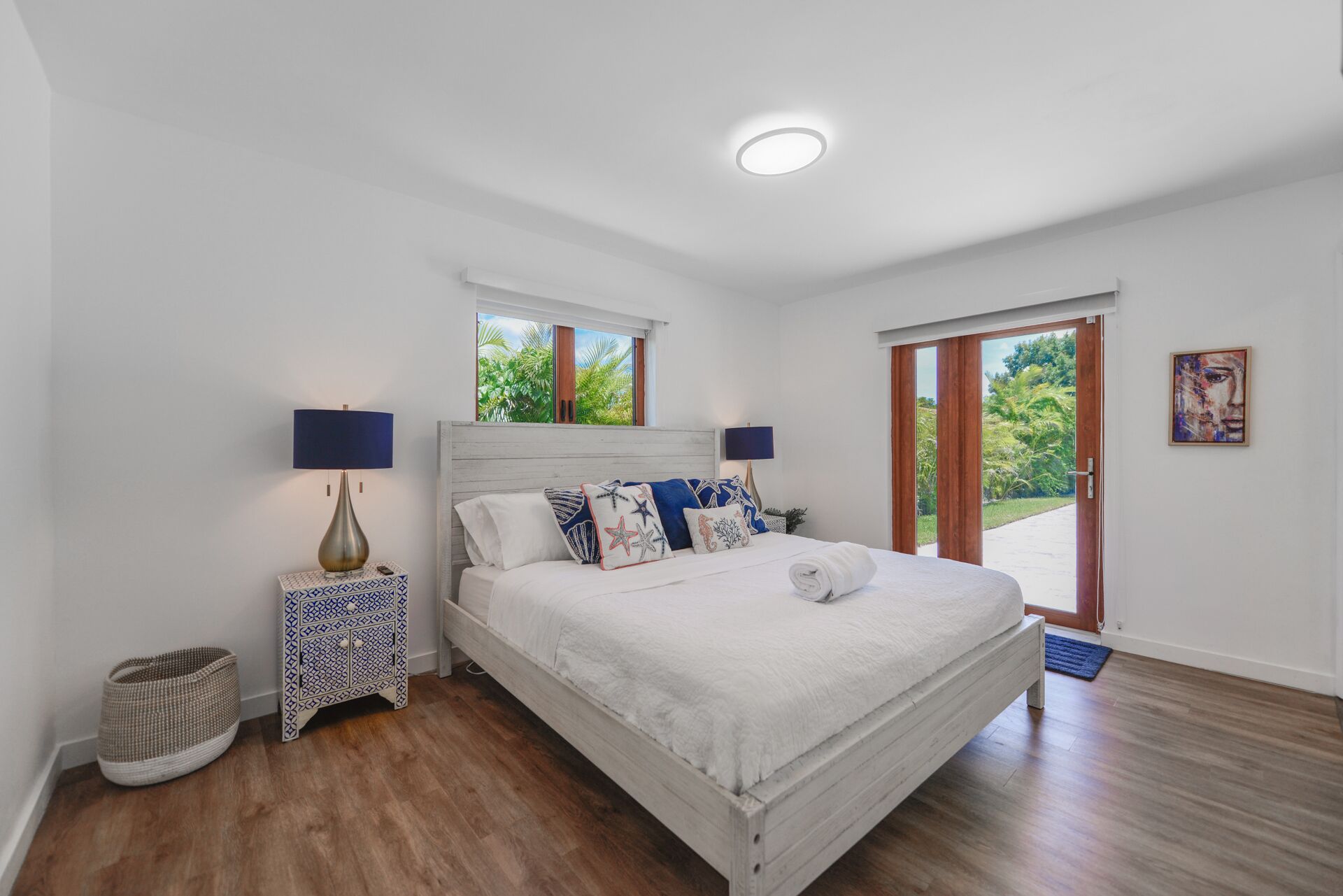 A bedroom with a bed, bedside tables, a window, and a door leading to an outdoor area.