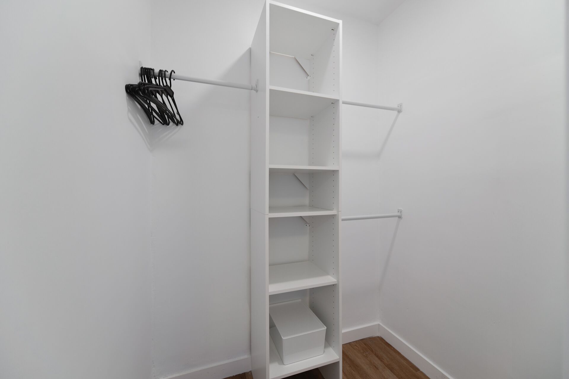A white closet with open shelves and a rod for hanging clothes.