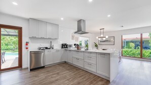 A modern kitchen with white cabinets, stainless steel appliances, and a large island. - Home in Westchester Miami - Private Pool (Miami)
