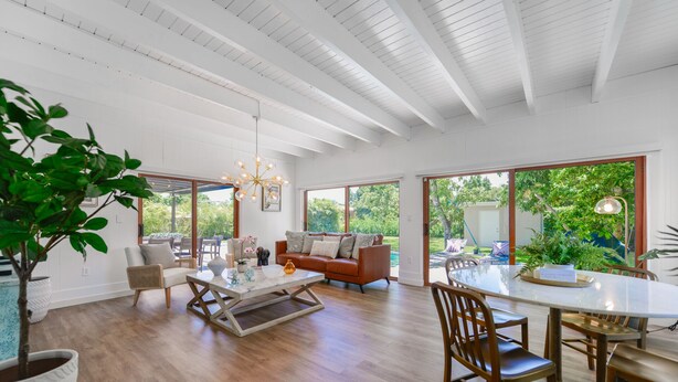 A spacious living room with a large window, a dining area with a round table, and a cozy seating area with a sofa. - Home in Westchester Miami - Private Pool (Miami)