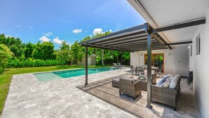 A covered outdoor area with a pool, patio furniture, and a view of the backyard. - Home in Westchester Miami - Private Pool (Miami)
