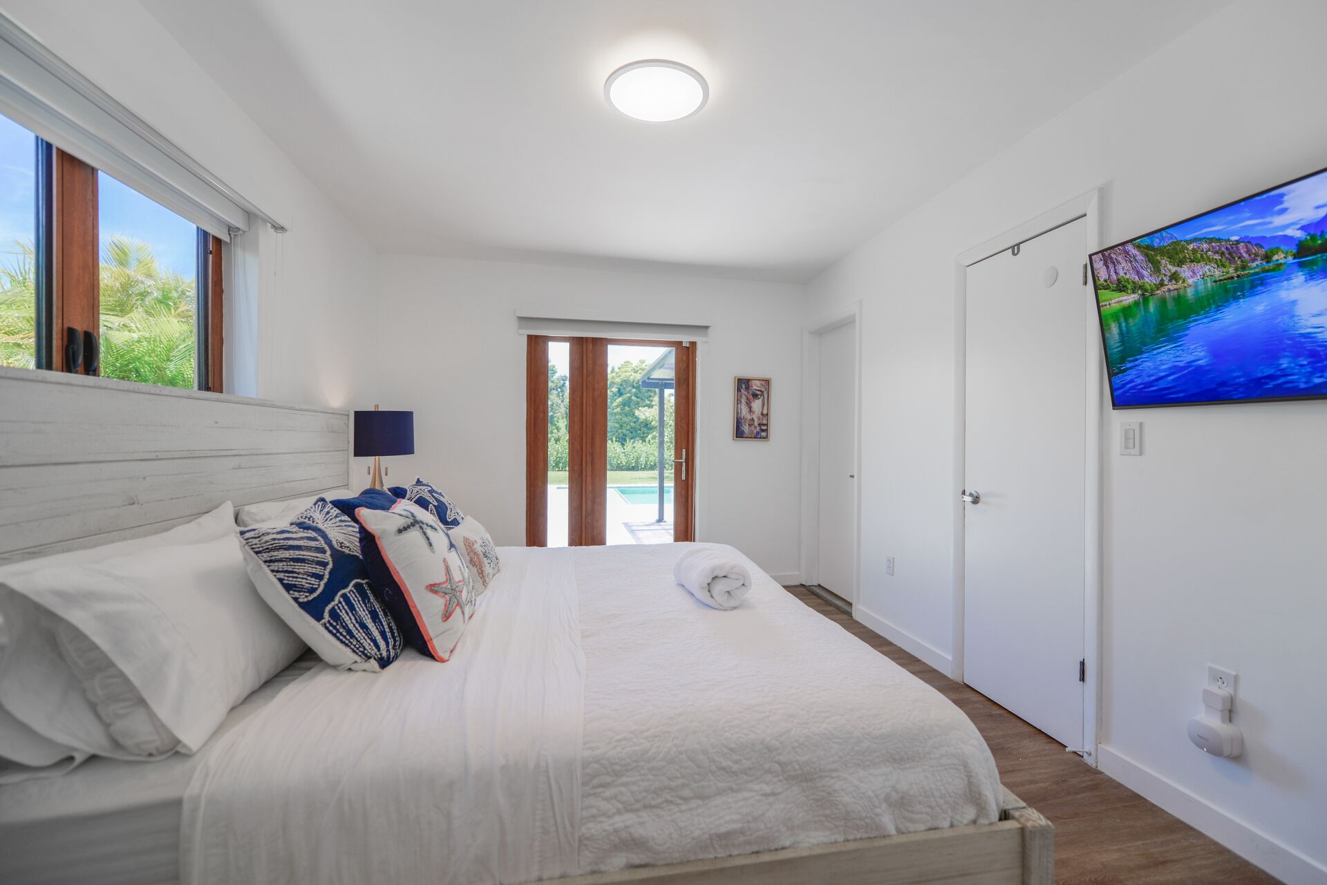 Un dormitorio con cama, televisor, puerta y ventana.