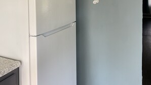 A kitchen with a white refrigerator, dark cabinets, and a wall with a branch of white flowers.