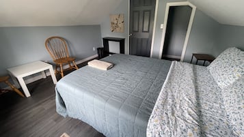 A bedroom with a bed, a chair, a small table, and a wardrobe.