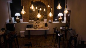 Interior acogedor de un restaurante con paredes de ladrillo visto, lámparas colgantes y una mesa central con comida y bebidas.