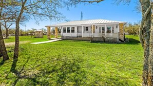 A single-story house with a covered porch, a small front yard, and a clear sky. - Charming, Hill Country Small-town Suite, Centrally located. (Harper)
