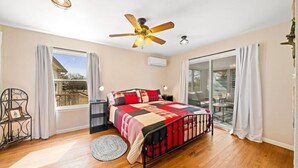 A bedroom with a bed, a ceiling fan, a window, and a sliding glass door. - Charming, Hill Country Small-town Suite, Centrally located. (Harper)