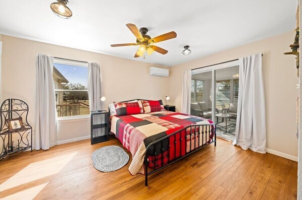A bedroom with a bed, a ceiling fan, a window, and a sliding glass door. - Charming, Hill Country Small-town Suite, Centrally located. (Harper)