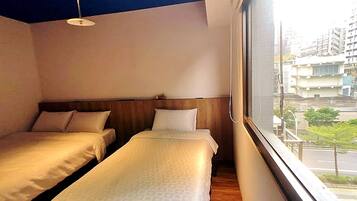 Hotellihuone, jossa on kaksi erillistä sänkyä, puinen pääty, kattovalaisin ja ikkuna, josta avautuu näkymä kaupunkiin.
