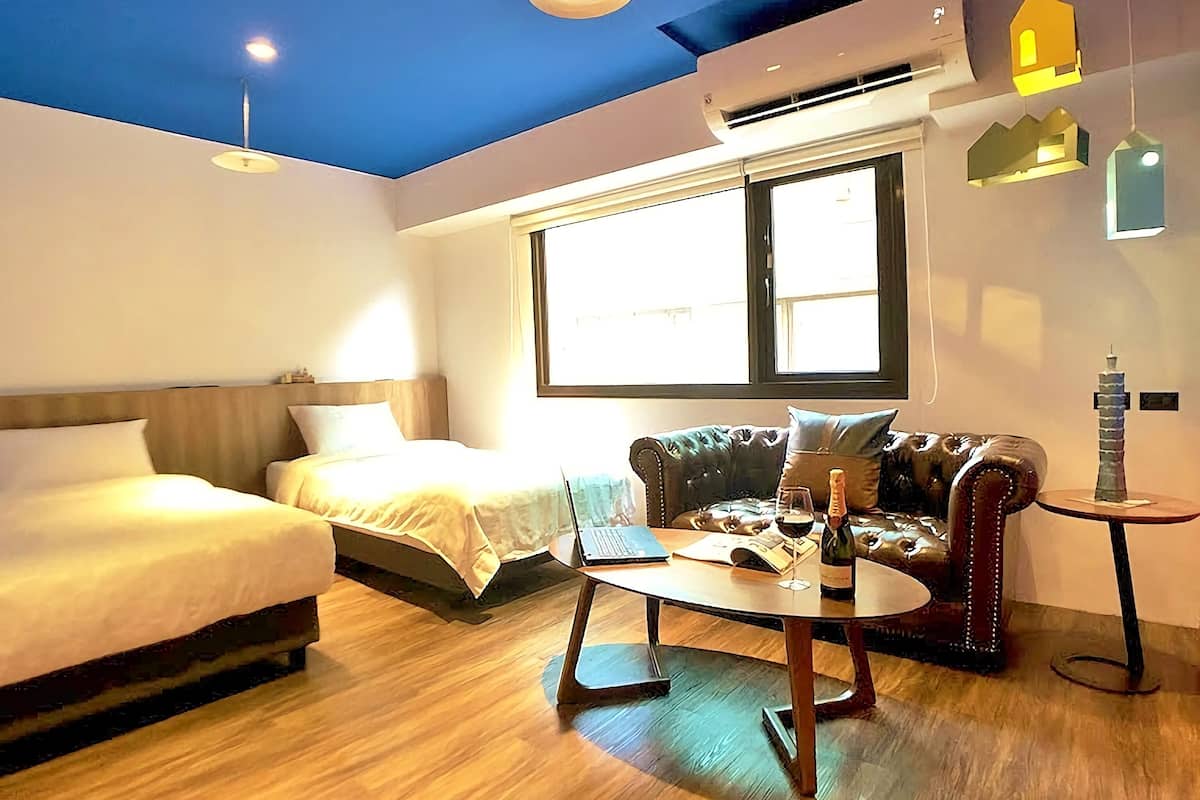 A hotel room with a bed, a sofa, a coffee table, and a window.