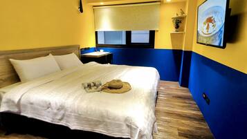 A hotel room with a bed, a nightstand, a window with blinds, a wall-mounted air conditioner, and a painting on the wall.
