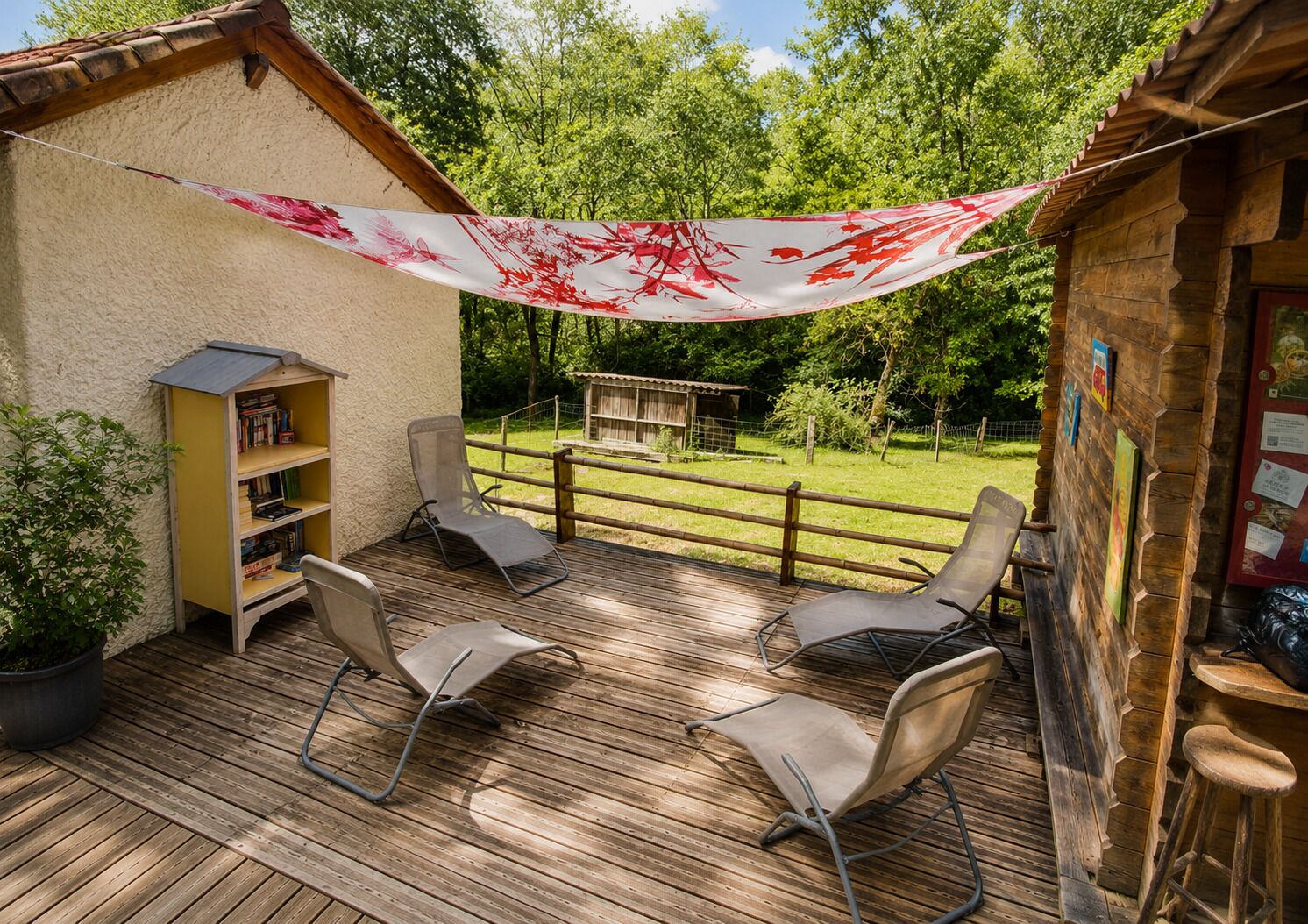 A wooden deck with metal chairs, a bookshelf, and a small wooden structure in the background.