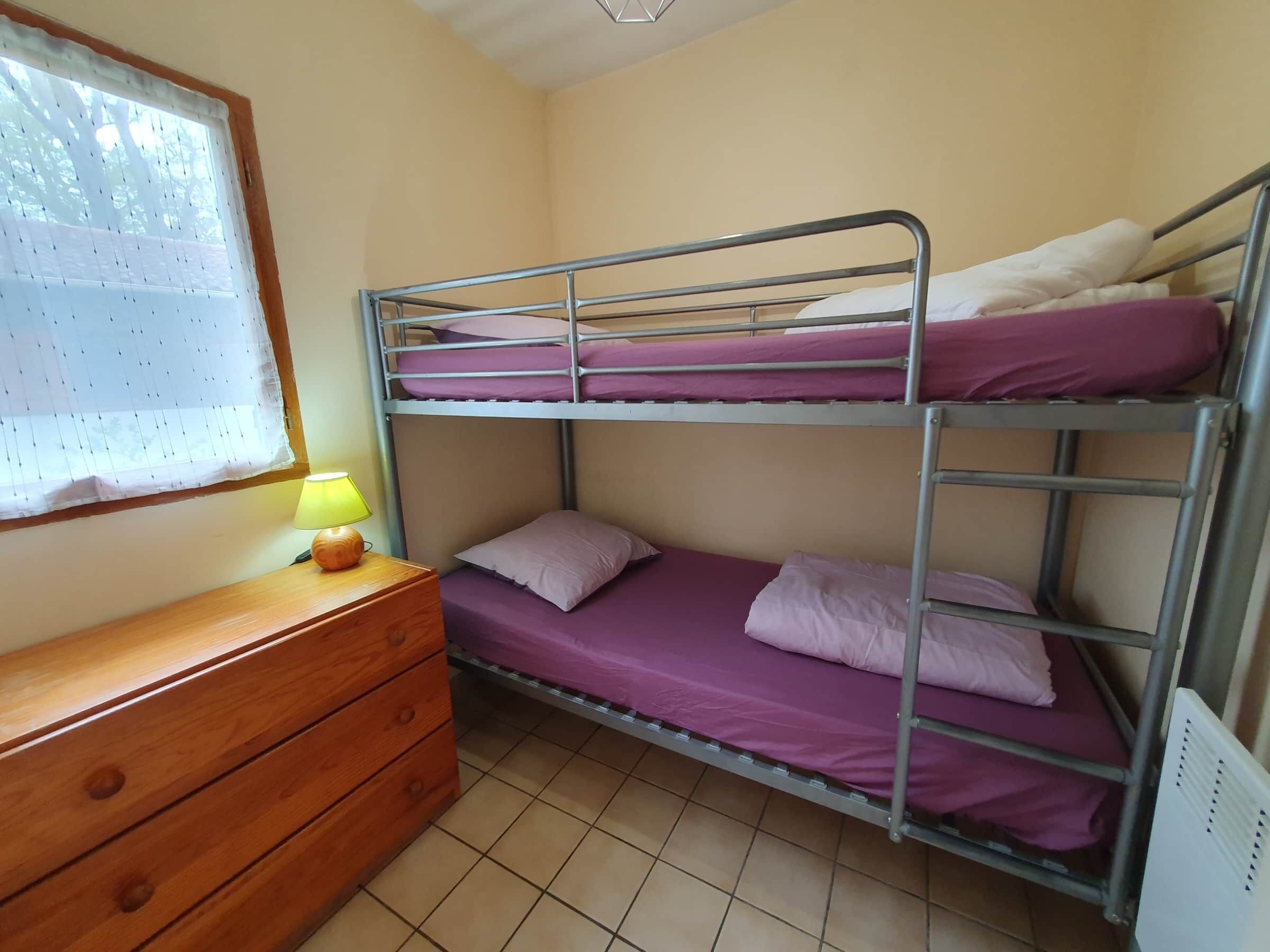 Dormitorio con literas, cómoda de madera y una lámpara.