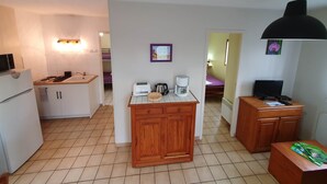A compact kitchen with a refrigerator, sink, and wooden cabinets. There is a small dining area with a table and chairs. - Cottage surrounded by nature (Noaillan)