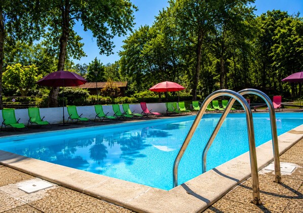 A swimming pool with lounge chairs and umbrellas, surrounded by trees. - Big Cottage - 6/8 people (Noaillan)