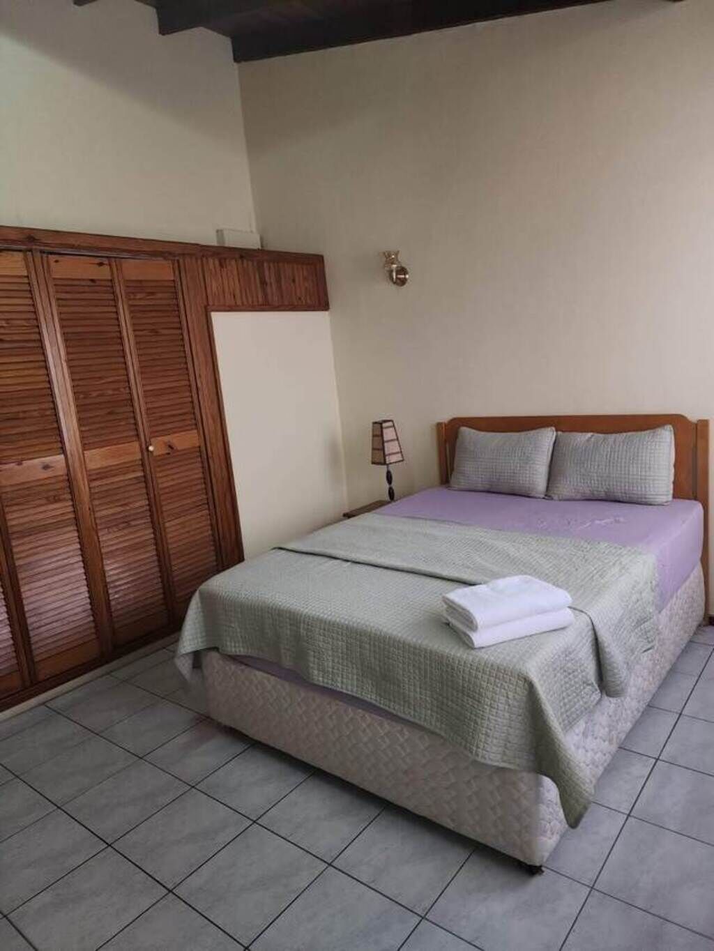 A bedroom with a bed, a wardrobe, and a nightstand.
