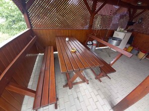 A wooden outdoor seating area with benches and a picnic table.