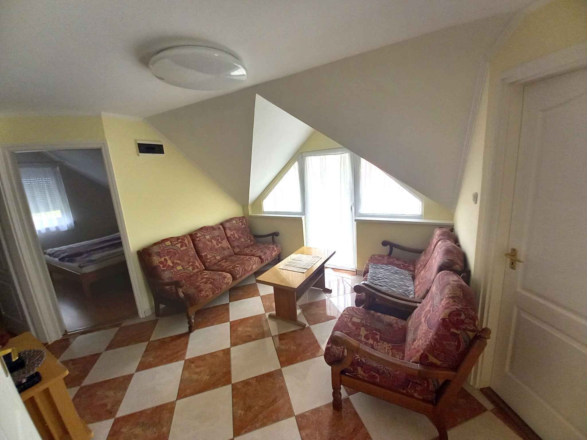 A room with a checkered floor, two patterned sofas, a small table, and a door.