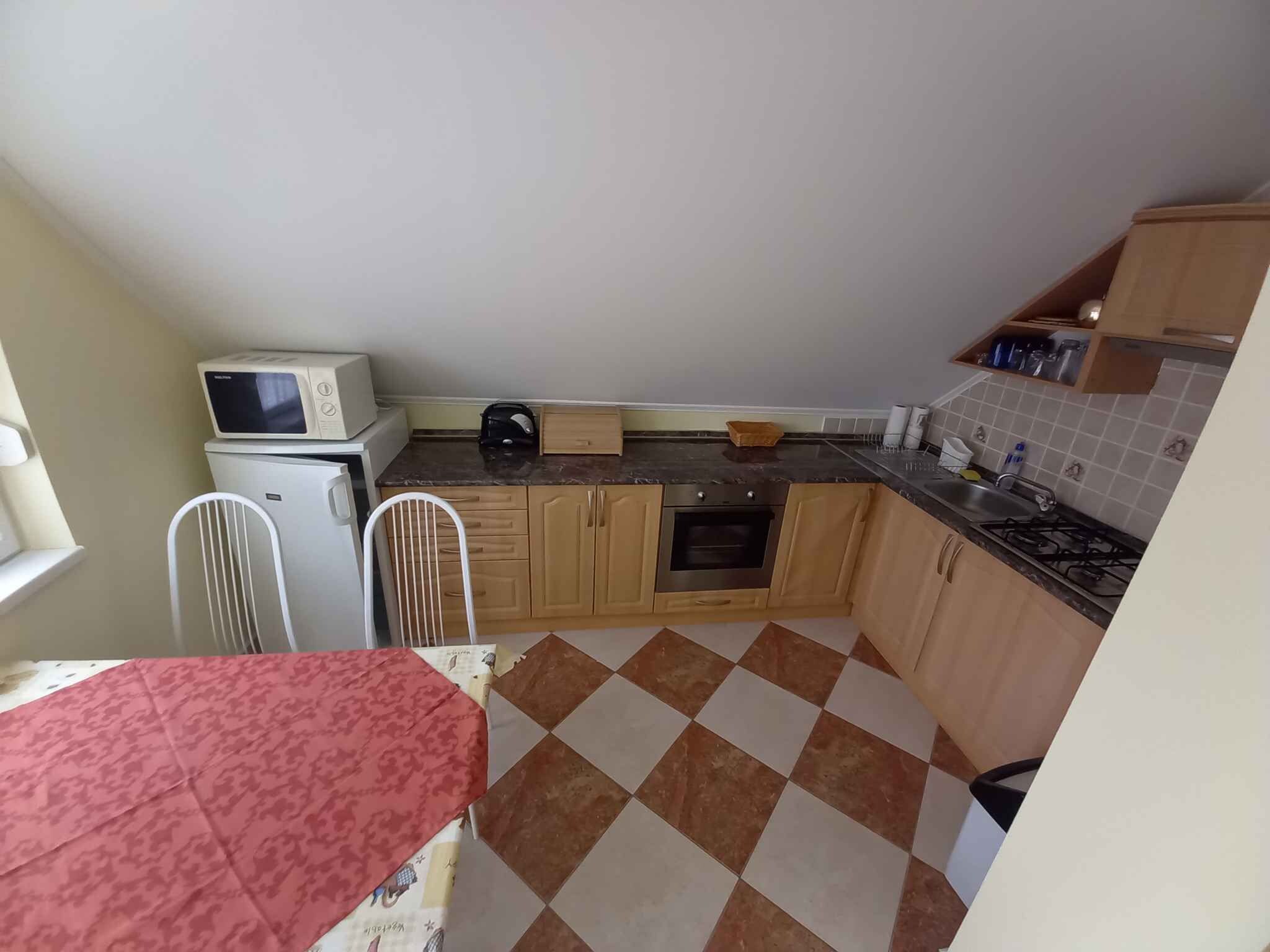 Une cuisine de taille réduite équipée d’un four à micro-ondes, d’une cuisinière et de meubles de rangement simples.