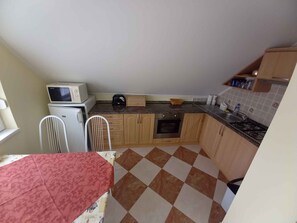A compact kitchen with a microwave, stove, and basic cabinetry.
