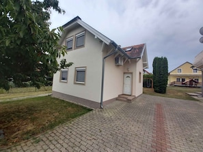 A two-story residential building with a tiled roof, a front door, and a small porch.