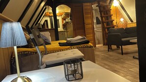 Ein gemütliches Schlafzimmer im Dachgeschoss mit einem Bett, einem Tisch mit einer Lampe und einem Sessel.