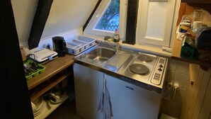 Eine kleine Küche mit Spüle, Herd und Fenster.