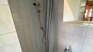 Ein Badezimmer mit Dusche, Waschbecken und Spiegel.
