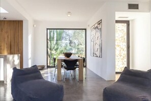Un salon moderne avec un coin repas, de grandes fenêtres et une vue sur la verdure.