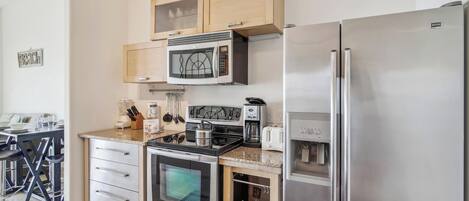 A modern kitchen with stainless steel appliances, wooden cabinets, and a countertop with a coffee maker and toaster.