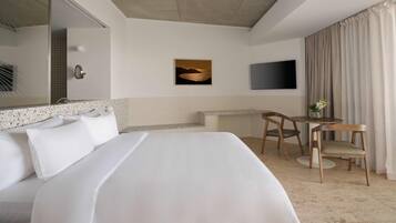 A hotel room with a large bed, a desk with a chair, a television, and a painting on the wall.