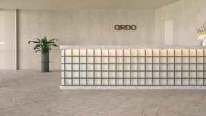 A reception desk with a glass panel design, a potted plant, and the word "ARDO" on the wall. - Ardo (Townsville)