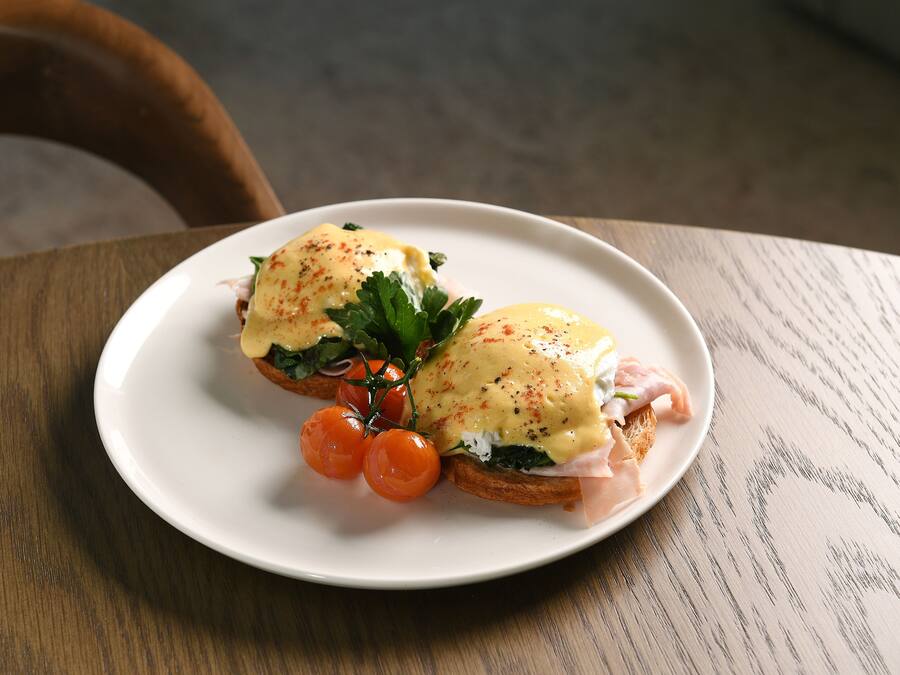 Un plato con un sándwich de huevo y tomates cherry sobre un plato blanco.