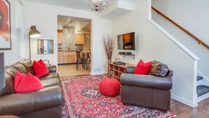 A modern living room with two leather sofas, a patterned rug, and a staircase. - South Side Bicycle Home Sleeps 6 (Pittsburgh)