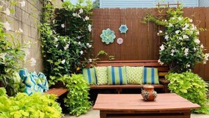 A wooden bench with cushions, a small table, and a decorative vase. - South Side Bicycle Home Sleeps 6 (Pittsburgh)