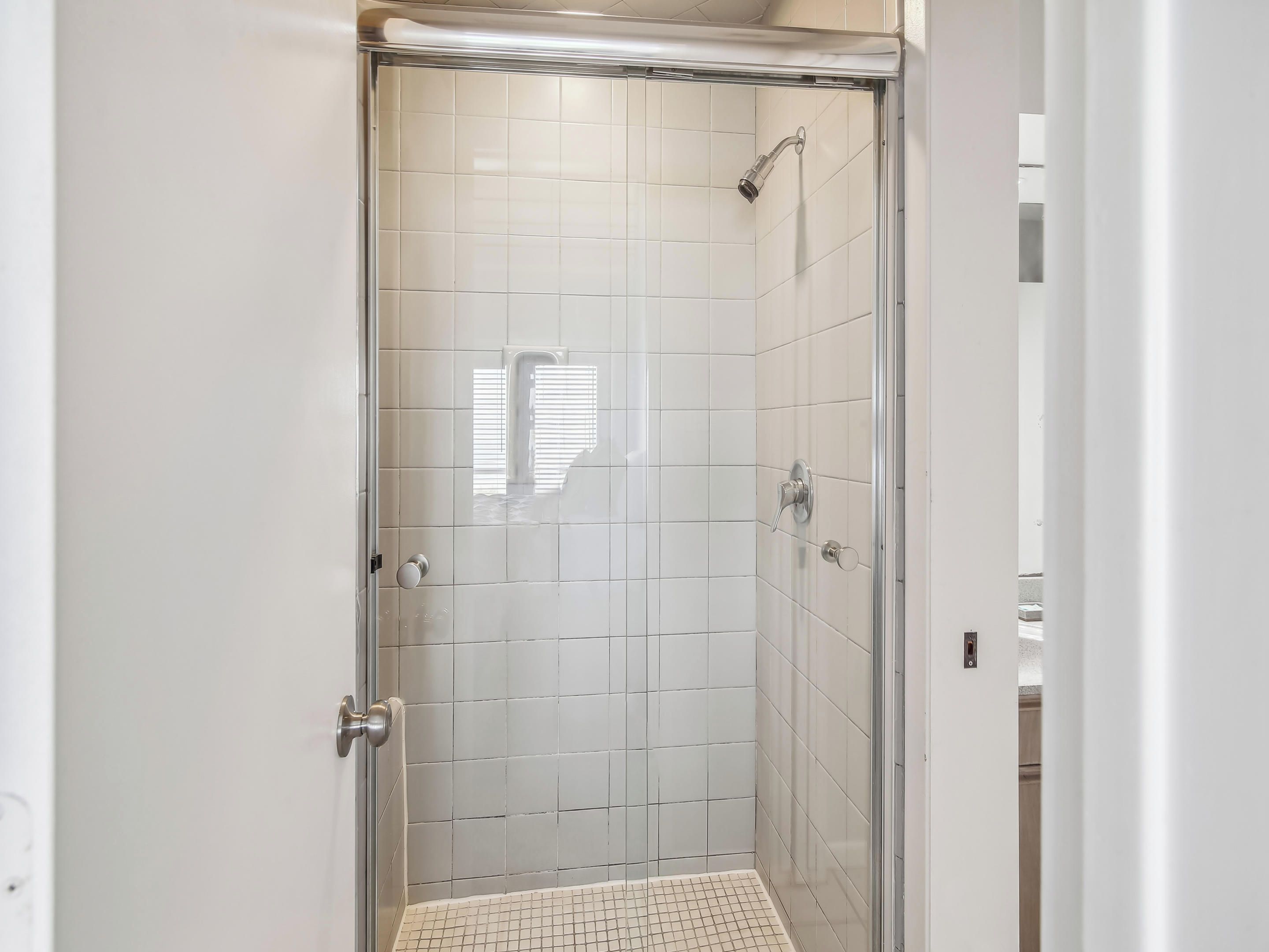 A walk-in shower with white tiles and a glass door.