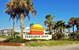 A sign for Terramar Beach with a clear view of the surrounding area including palm trees and beach houses.