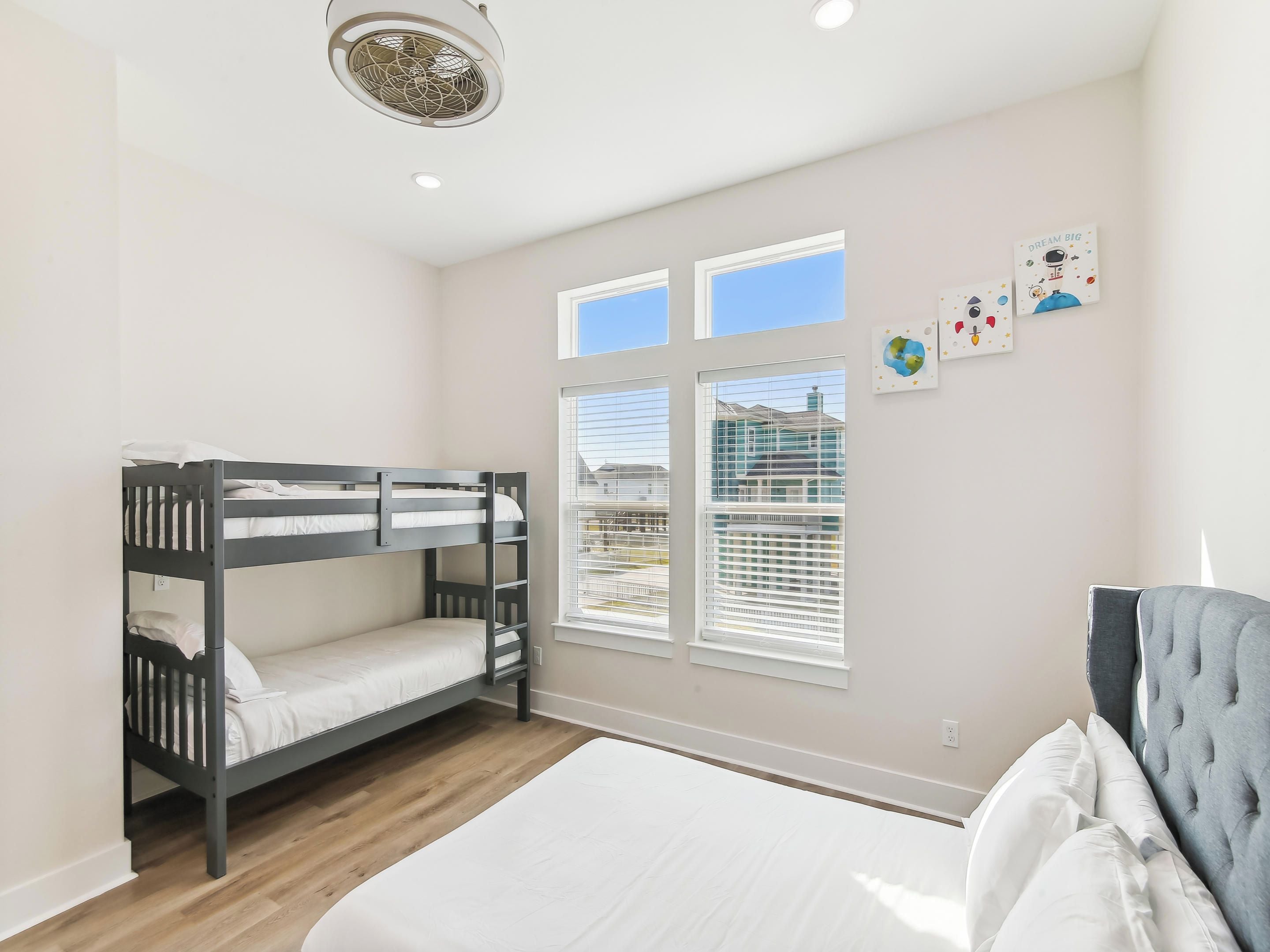 A bedroom with bunk beds, a large bed, and a window with blinds.