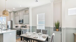 Una cocina moderna con gabinetes grises, una isla central y una zona de comedor con una mesa dispuesta para cuatro.