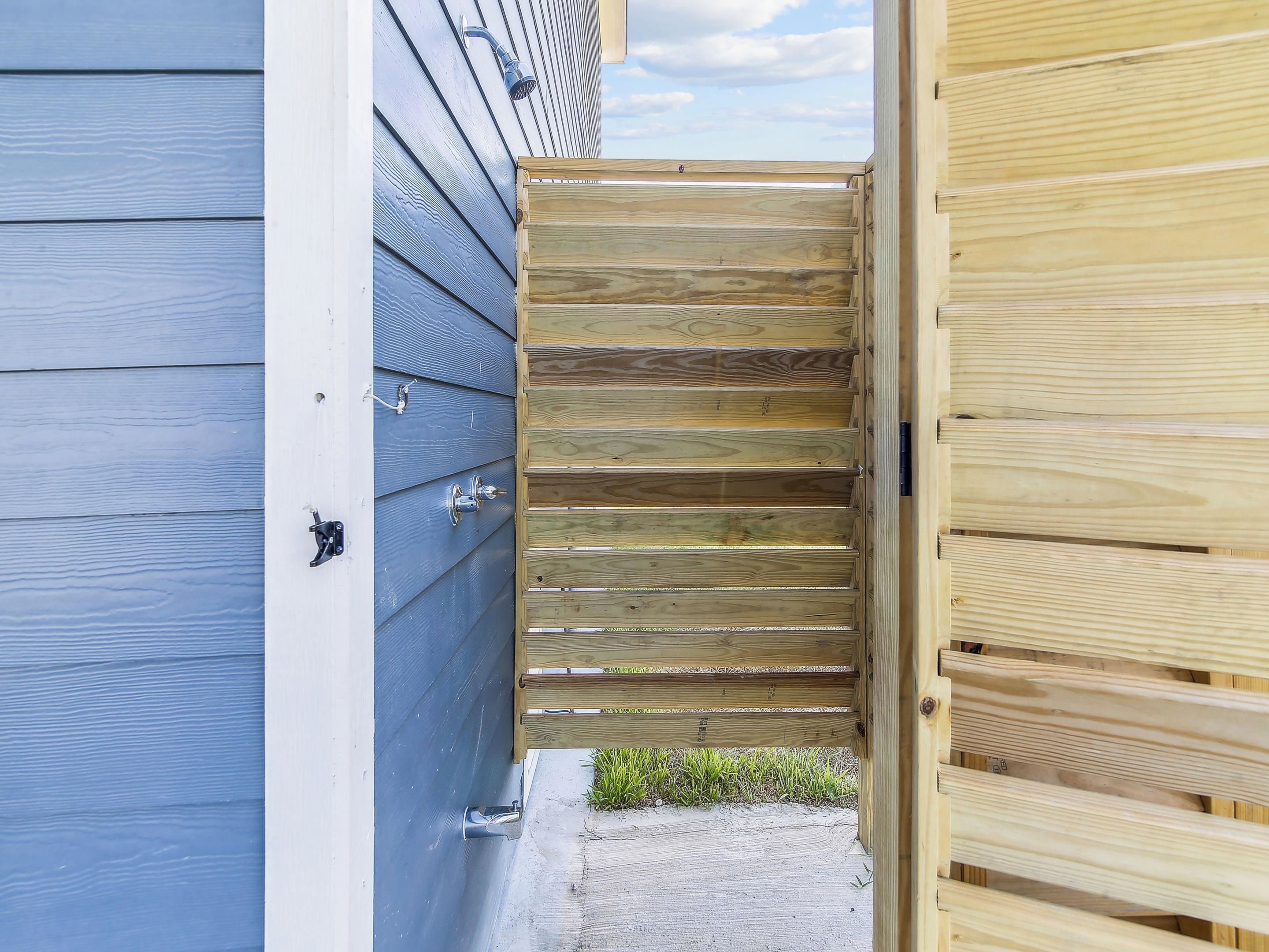 A wooden gate leading to a building with a blue exterior.