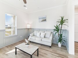 A modern living room with a white sofa, a marble coffee table, and a potted plant.