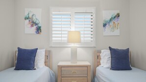 Un dormitorio con dos camas, una mesita de noche con lámpara y obras de arte en las paredes.