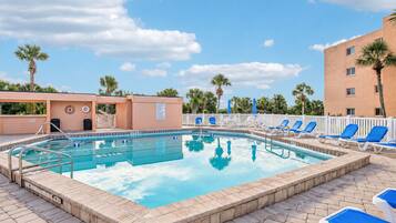 A swimming pool with lounge chairs and a palm tree in the background.
