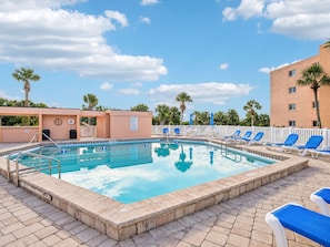 A swimming pool with lounge chairs and a palm tree in the background. - Beach & Tennis 217 by Distinctive Beach Rentals (St. Augustine)