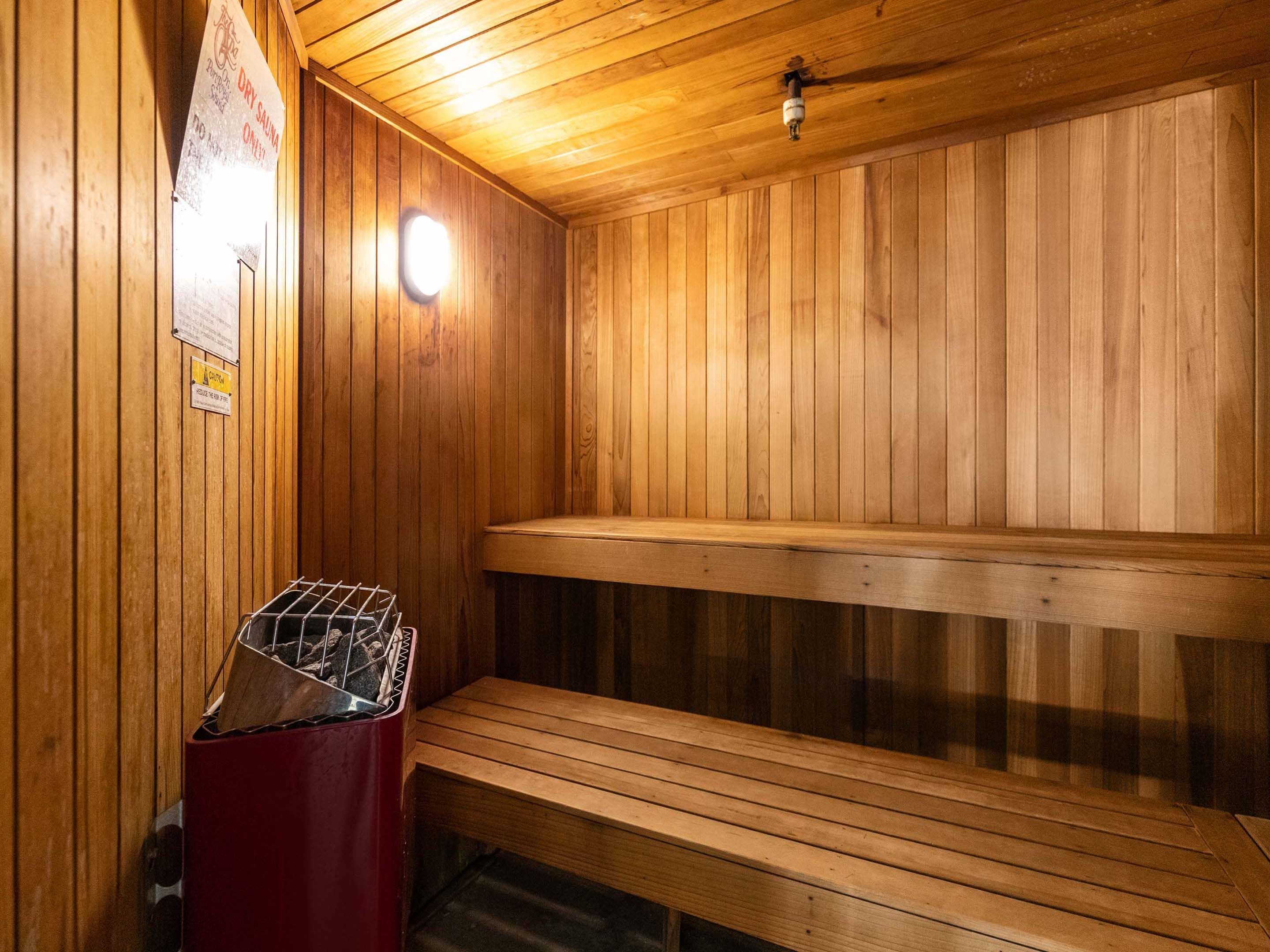 A sauna with wooden benches and a metal grate for burning wood.