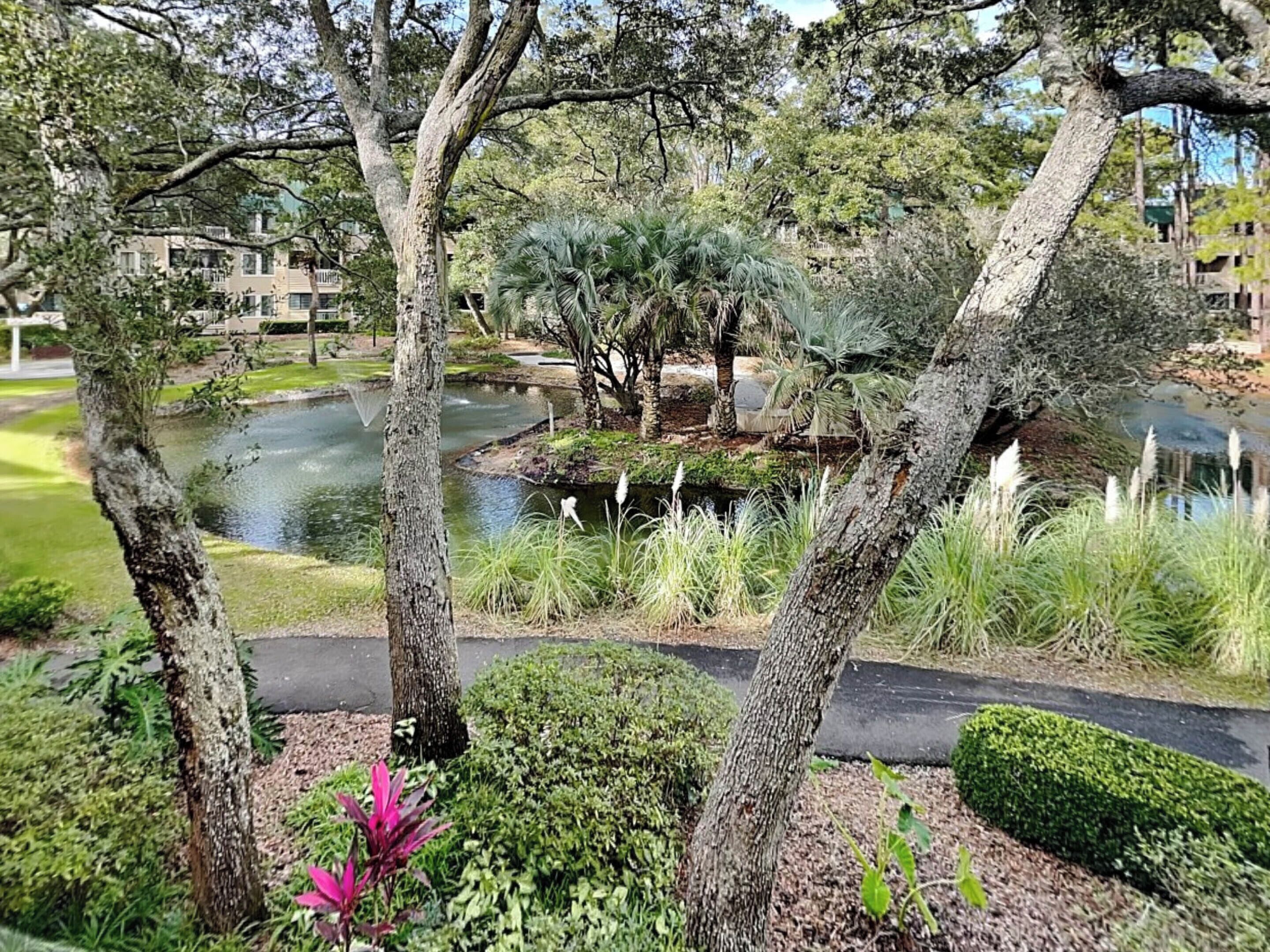 A landscaped garden with a pond, trees, and a pathway.