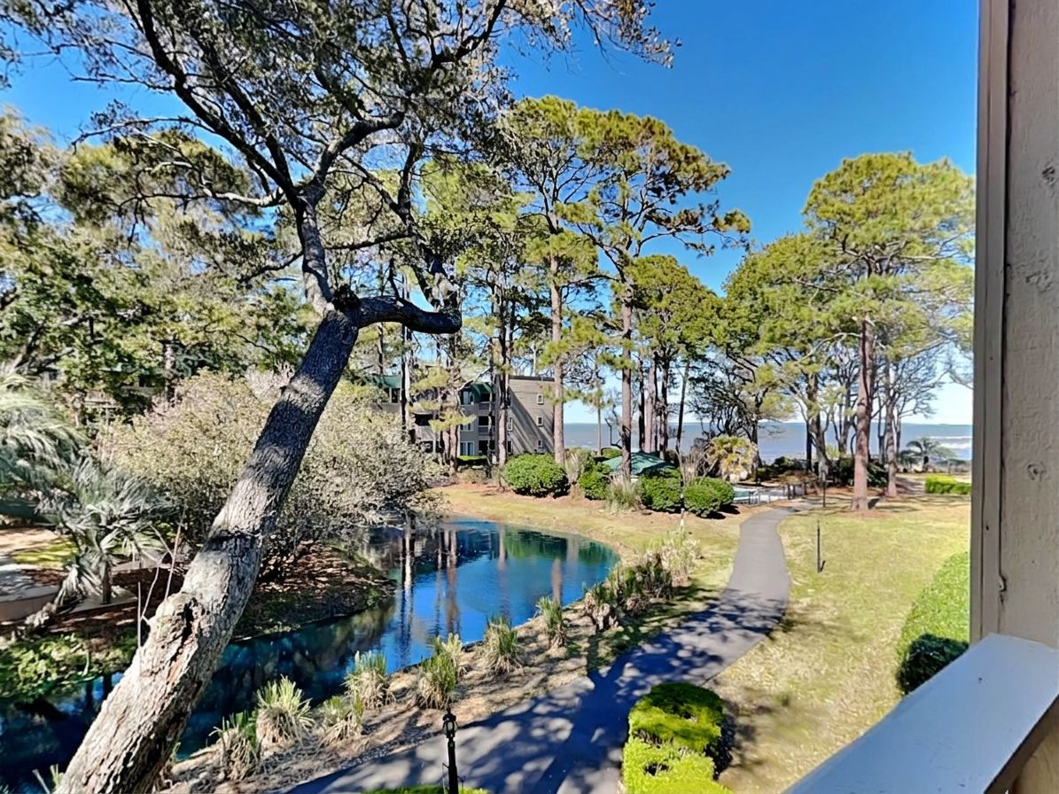A pool area with a clear view of the surrounding landscape, including trees and a building in the background.