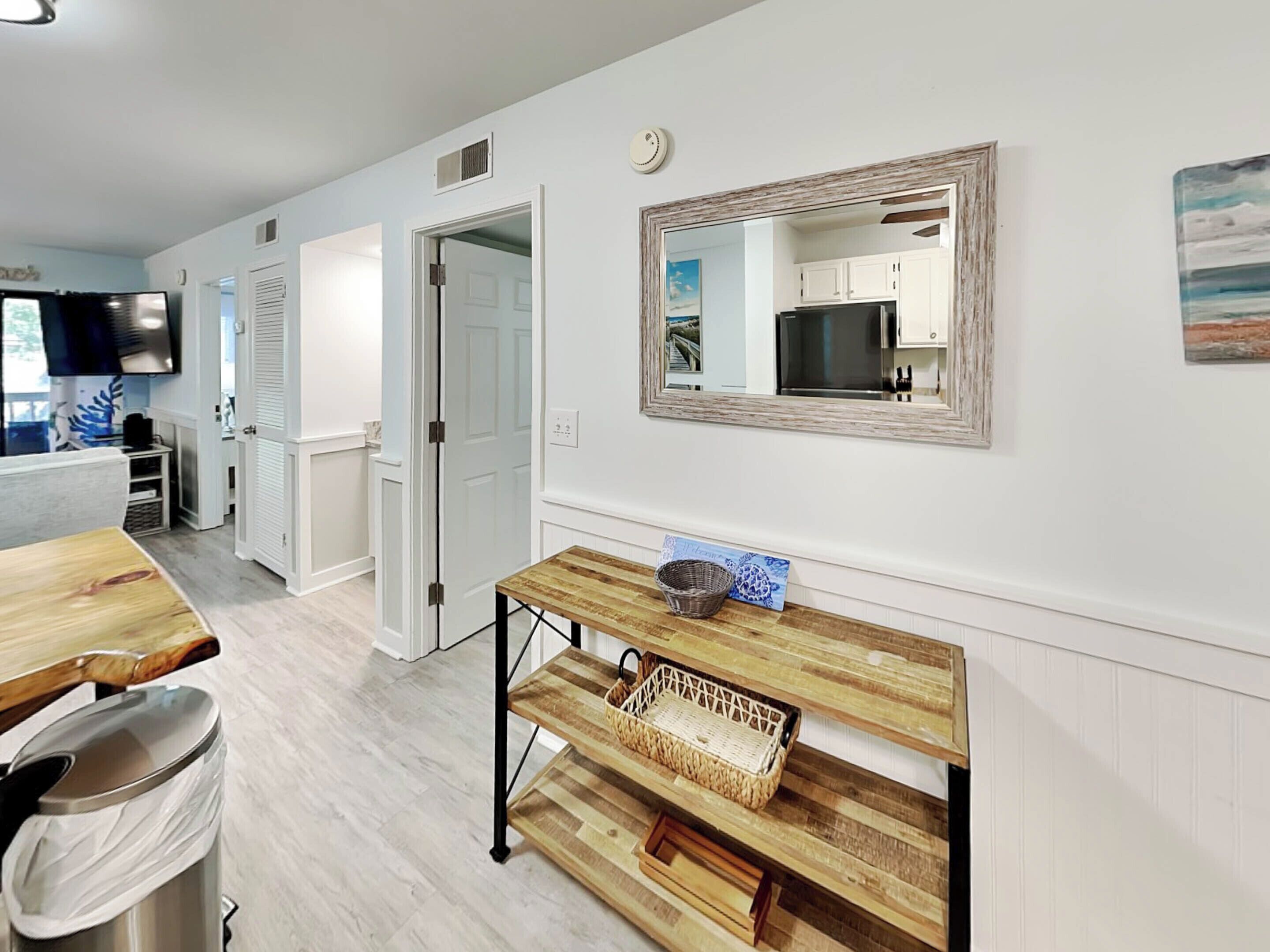 Una cocina moderna con armarios blancos, una mesa de madera y un espejo grande.